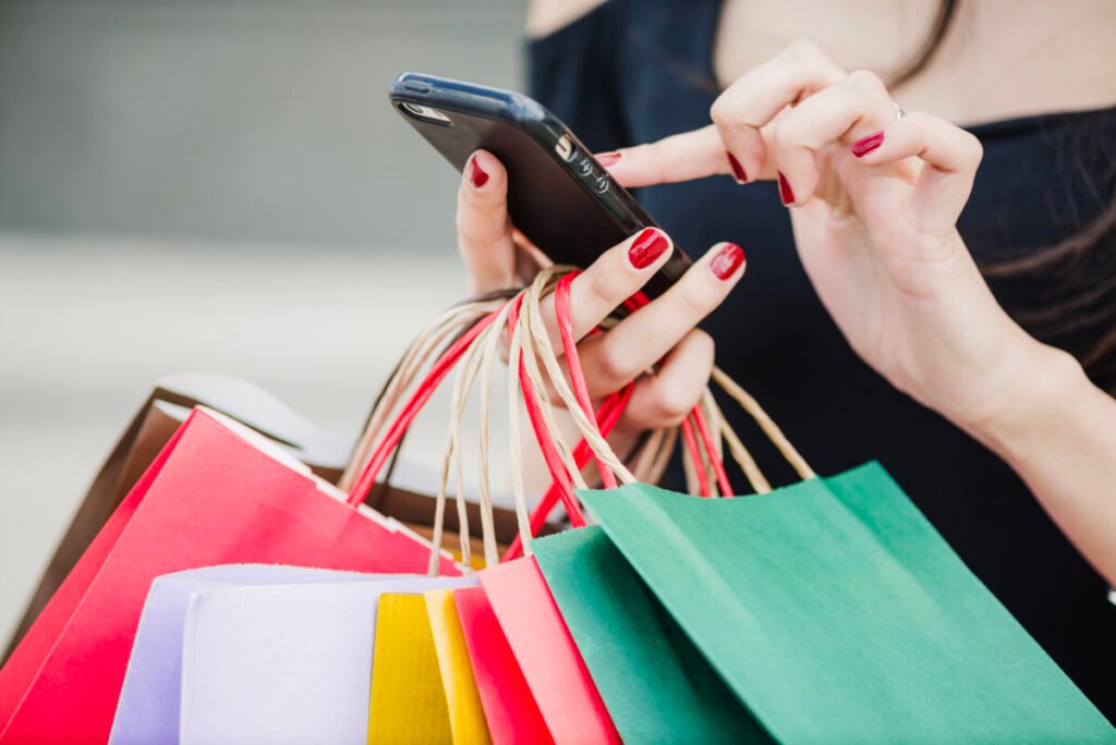Woman with shopping bags holding smartphone